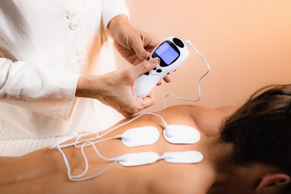 Upper Back Physical Therapy with TENS Electrode Pads, Transcutaneous Electrical Nerve Stimulation. Therapist Positioning Electrodes onto Patient's Upper Back