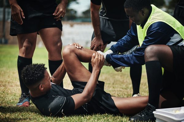 Cropped shot of a young rugby player receiving first aid assistance on the field